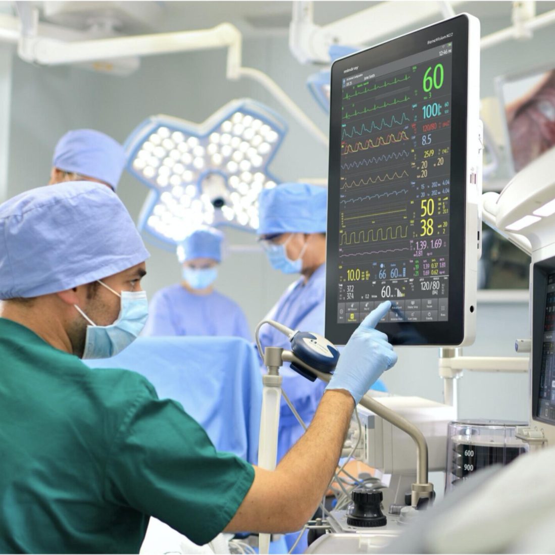 Anaesthesiologist monitoring a patient during surgery in a modern operating room with anaesthesia equipment and vital signs monitors.